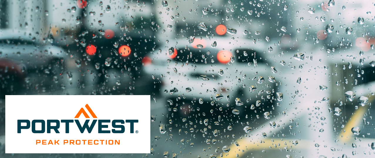 Calle empapada de lluvia con coches fotografiados a través de una ventana cubierta de gotas de lluvia. En la esquina inferior izquierda está el logotipo de Portwest en azul y naranja sobre un fondo blanco.