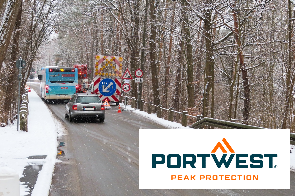 Escena de construcción con autobús y coche en una carretera nevada rodeada de árboles. En la esquina derecha está el logo de la marca Portwest. Hay un enlace a la colección de ropa térmica y frigorífica.
