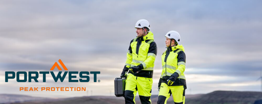 La imagen muestra a un hombre y una mujer con ropa de trabajo amarilla y cascos blancos. Caminan por un sendero de grava. Al fondo, se ven una cadena de colinas y un cielo azul con nubes. El logotipo azul y naranja de Portwest se encuentra en la esquina inferior izquierda.