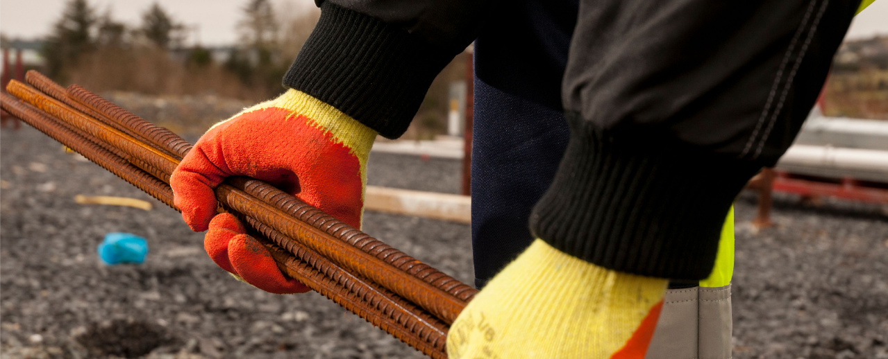 Imagen del modelo del guante Fortis Grip A150 en amarillo/naranja trabajando con armadura.