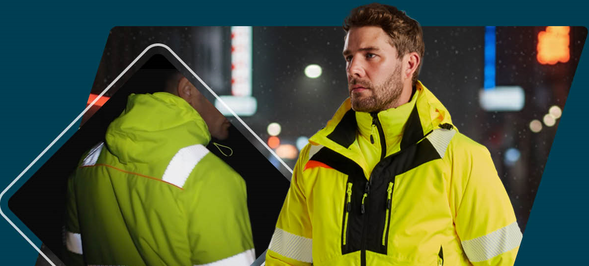 Un trabajador con ropa amarilla de alta visibilidad con bandas reflectantes y detalles negros. Al fondo, se ve una calle oscura con iluminaci&oacute;n borrosa. La parte trasera de la chaqueta se muestra a la izquierda.