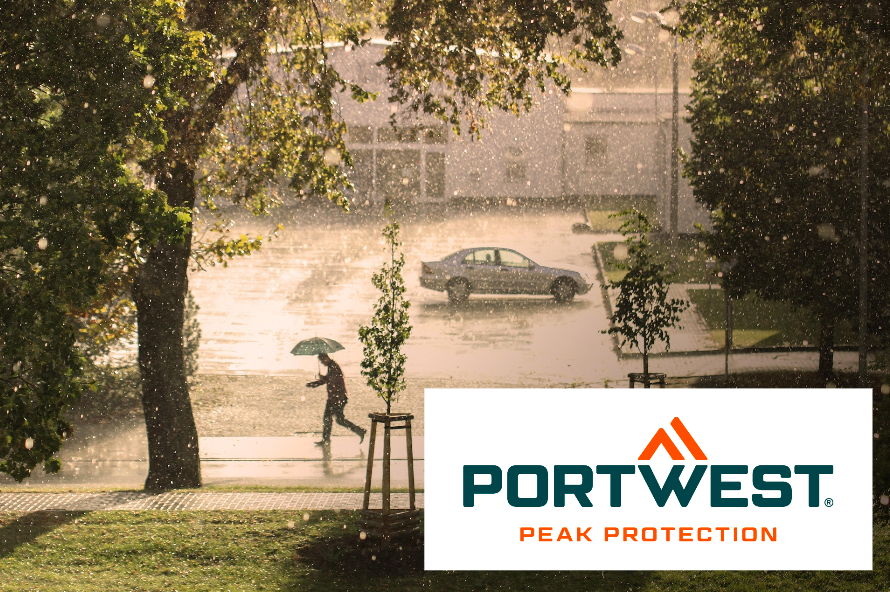 Vista de una calle bajo la lluvia. Una persona con paraguas cruza la calle y el sol brilla aunque está lloviendo. El logotipo del fabricante Portwest se encuentra en la esquina inferior derecha de la imagen. Se proporciona un enlace a nuestra ropa para la lluvia.