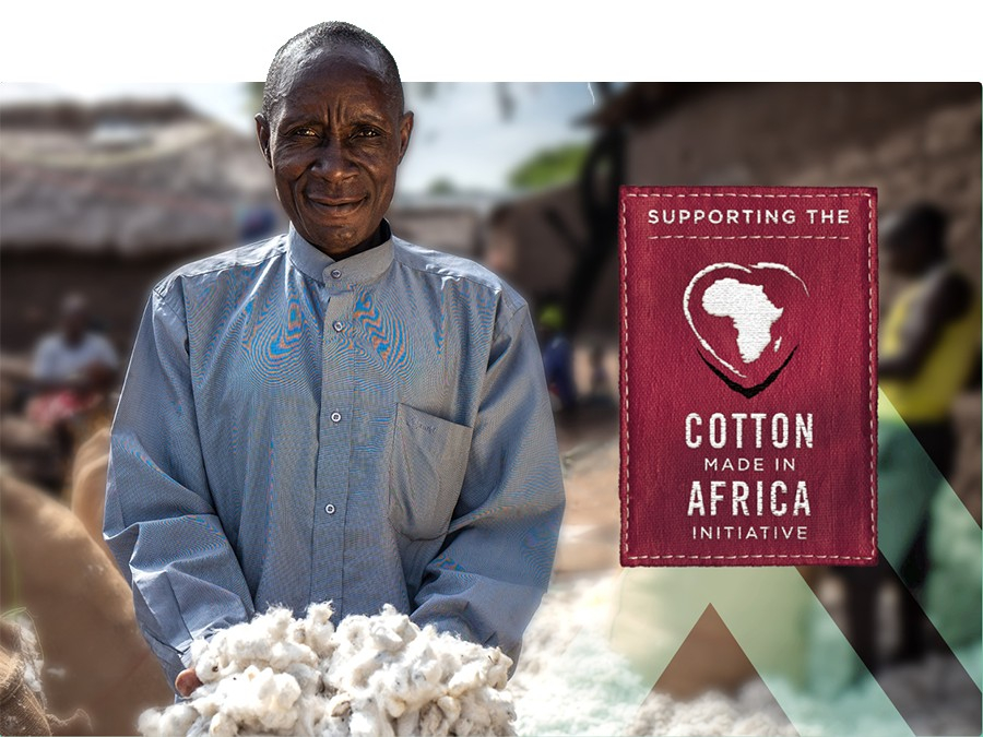 Granjero africano que lleva una camisa azul y presenta un puñado de algodón. En la mitad derecha de la imagen hay un letrero de color rojo oscuro que dice "Apoyo a la iniciativa Cotton Made In Africa".