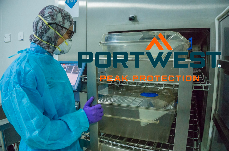 Persona con ropa desechable azul frente a un armario de acero inoxidable. El logotipo del fabricante Portwest en naranja y azul se encuentra en la parte derecha de la imagen. Hay un enlace a nuestra ropa de laboratorio.