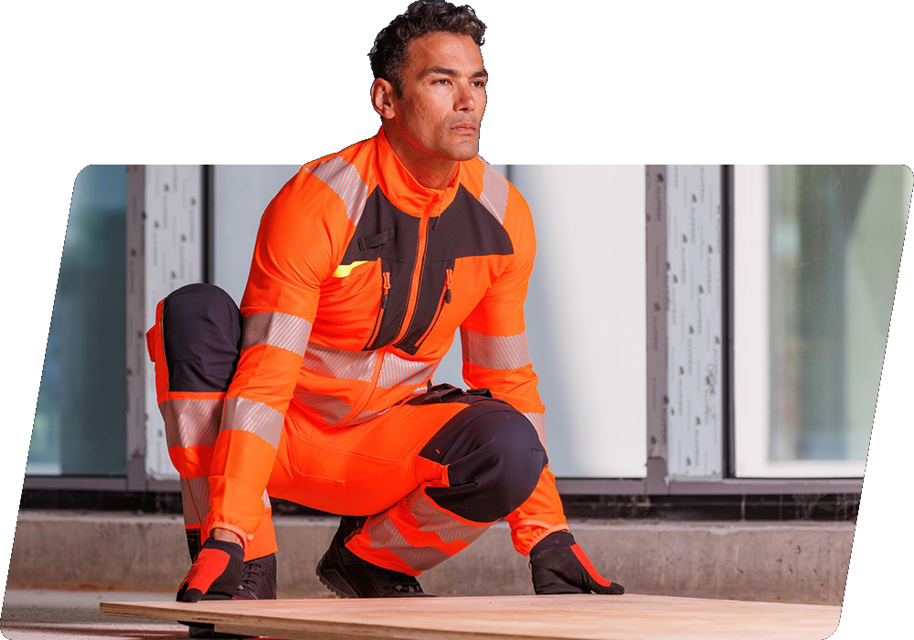 Un trabajador de cabello oscuro con ropa naranja de alta visibilidad levanta un panel de madera del suelo. Hay un enlace a nuestra colección DX4.