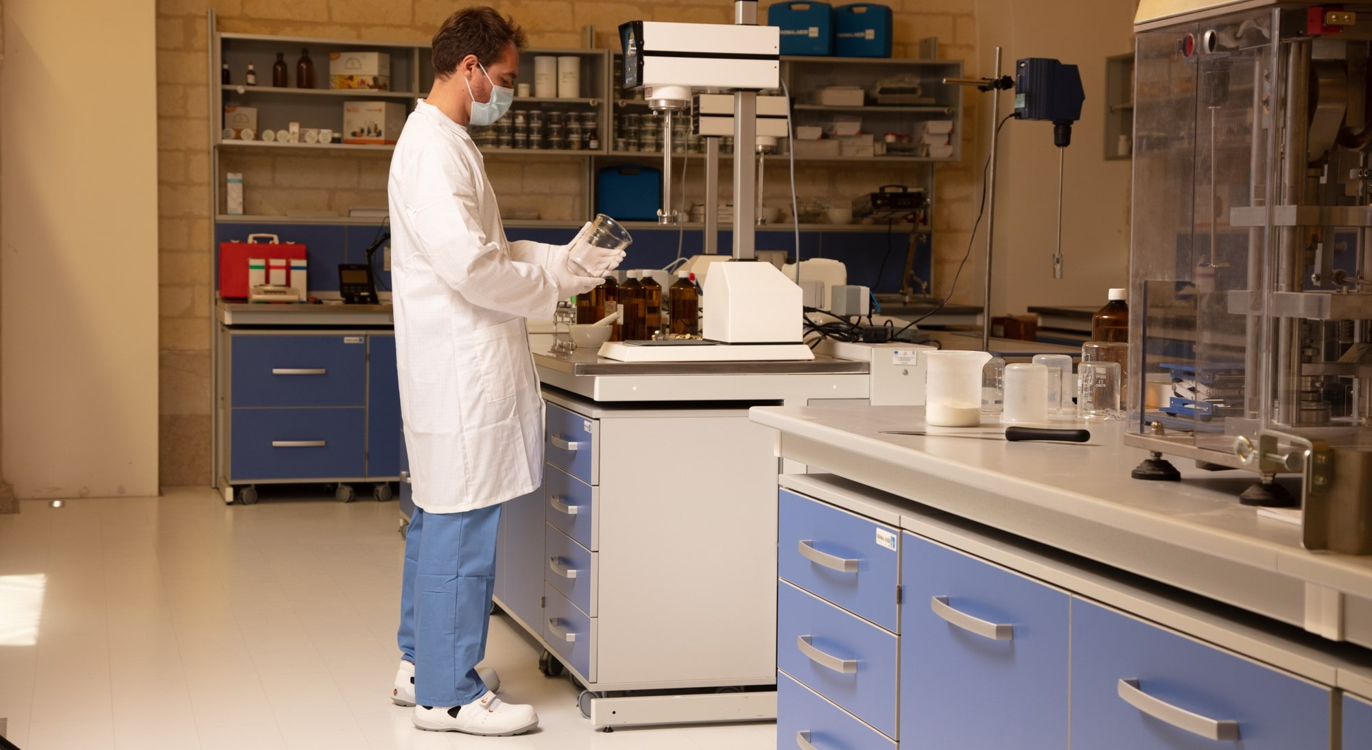Técnico de laboratorio con bata blanca y ropa protectora antiestática trabajando en el laboratorio con un enlace vinculado a la bata de trabajo antiestática.